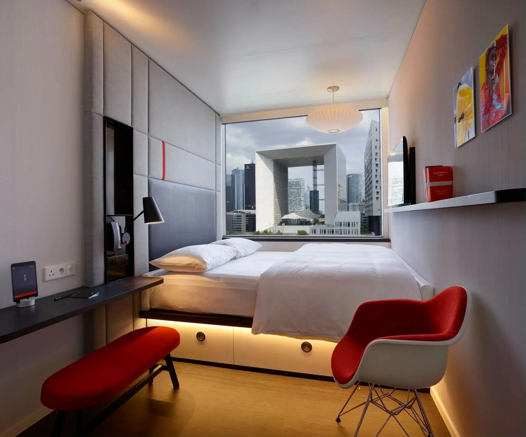 Inside a citizenM hotel bedroom looking across the king-sized bed out the window at Paris' La Defence building